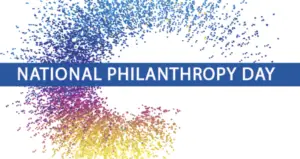 “NATIONAL PHILANTHROPY DAY” text centered over a swirling pattern of blue, purple, and yellow dots representing the community homeworks of Kalamazoo.