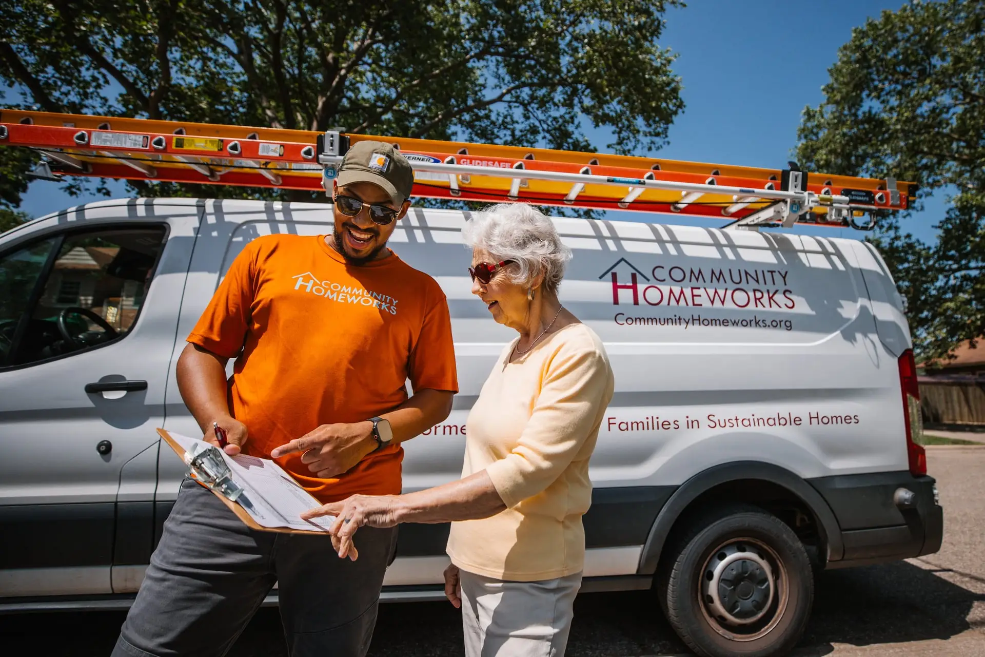 Woman and man looking at a clipboard standing in front of a white van.