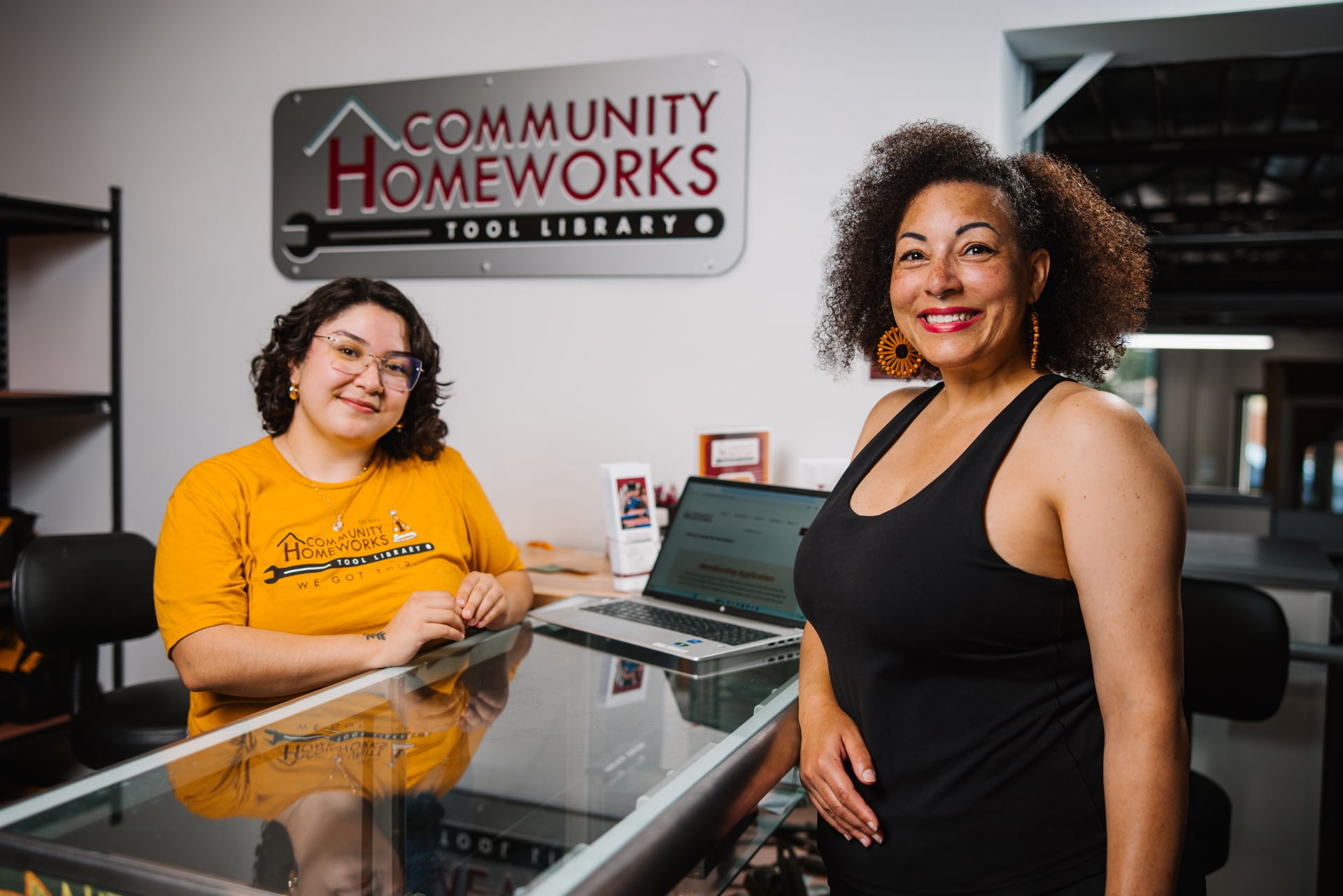 Two woman standing at the Community Homeworks front desk.