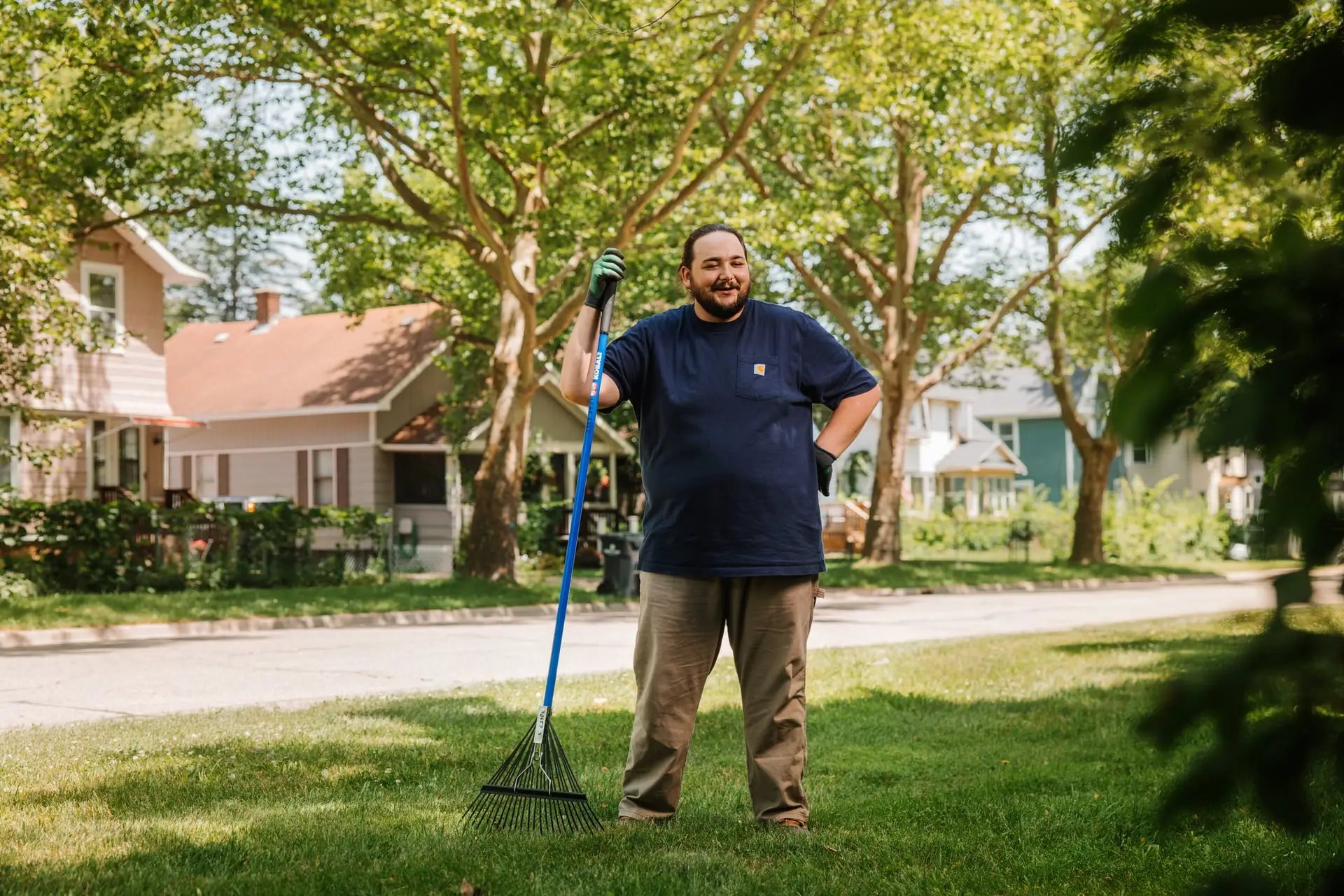 Man standing in the grass with a rake in his hand.