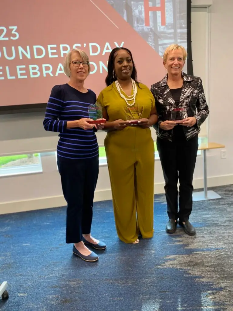 Three woman standing next to each other at the founders day celebration at Community Homeworks.